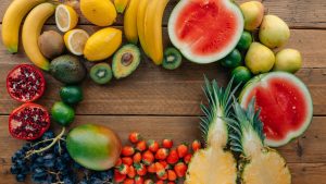 Colorful assortment of fresh fruits in a flatlay on wooden surface, perfect for healthy lifestyle themes.
