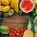 Colorful assortment of fresh fruits in a flatlay on wooden surface, perfect for healthy lifestyle themes.